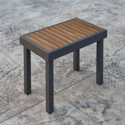 Modern outdoor side table with brown wooden slatted top and black metal frame legs on concrete surface