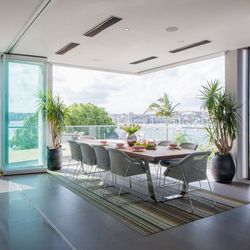 Striped area rug in green and gray tones on modern dining room floor with waterfront view.